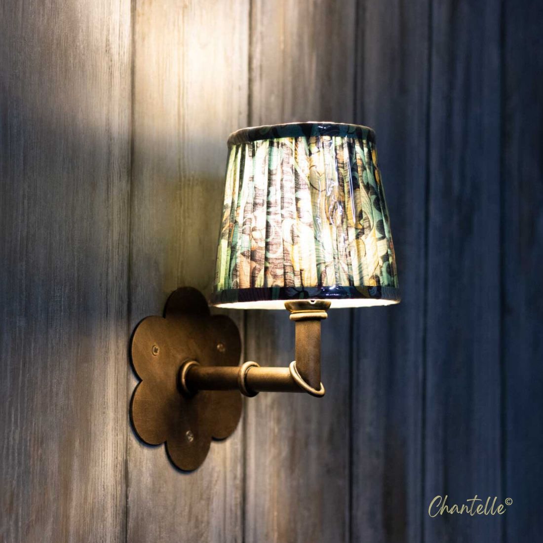 Antique brass wall light with patterned pleated shade and flower cut backplate